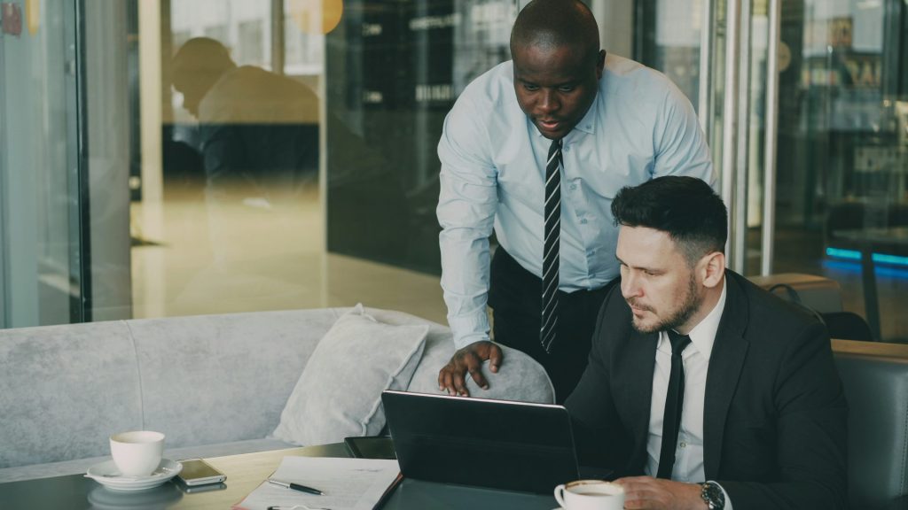 Two businessmen collaborating over a laptop.